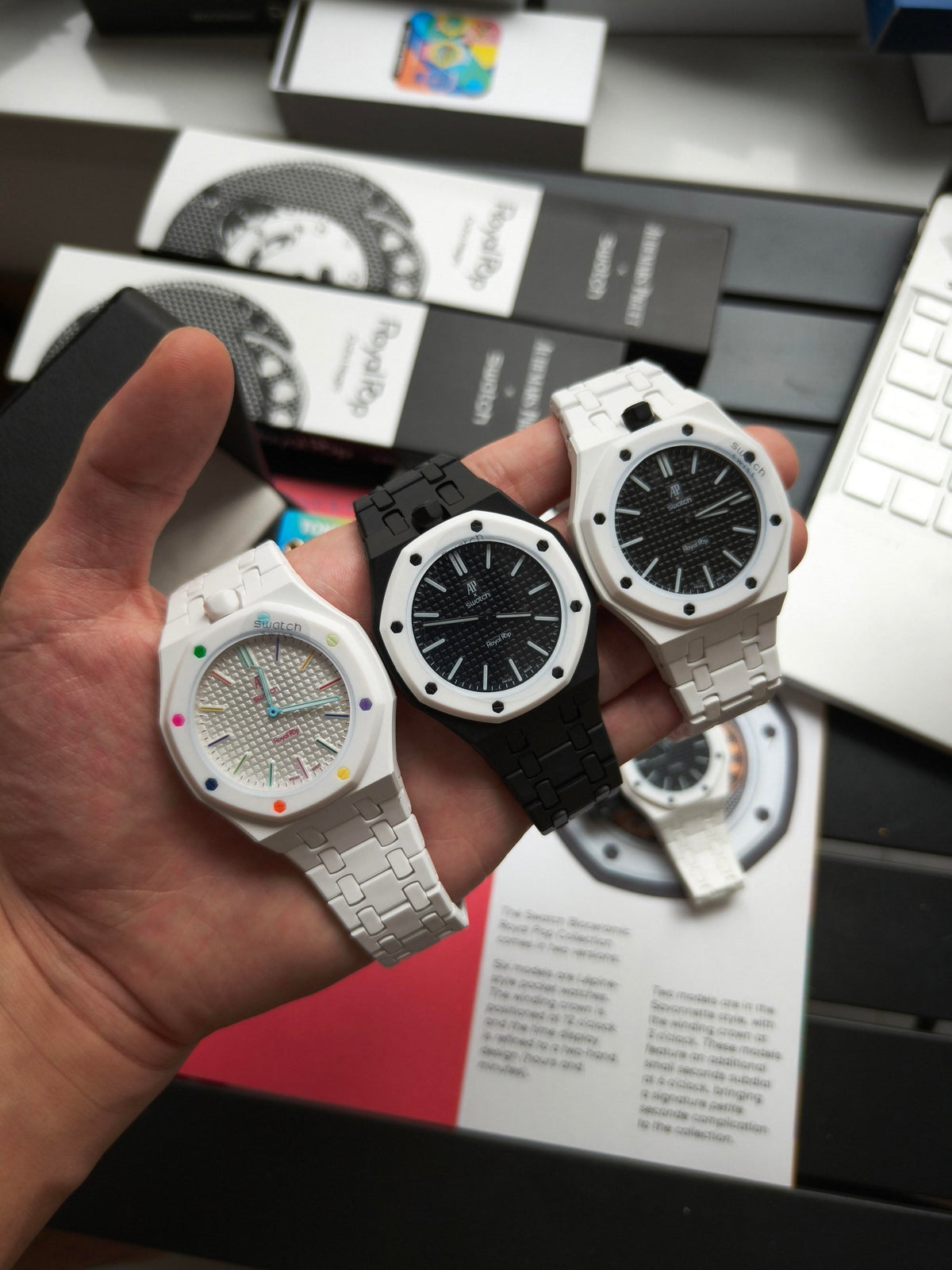 Three Royal Pop watches with black and white wrist conversion bracelets held in hand