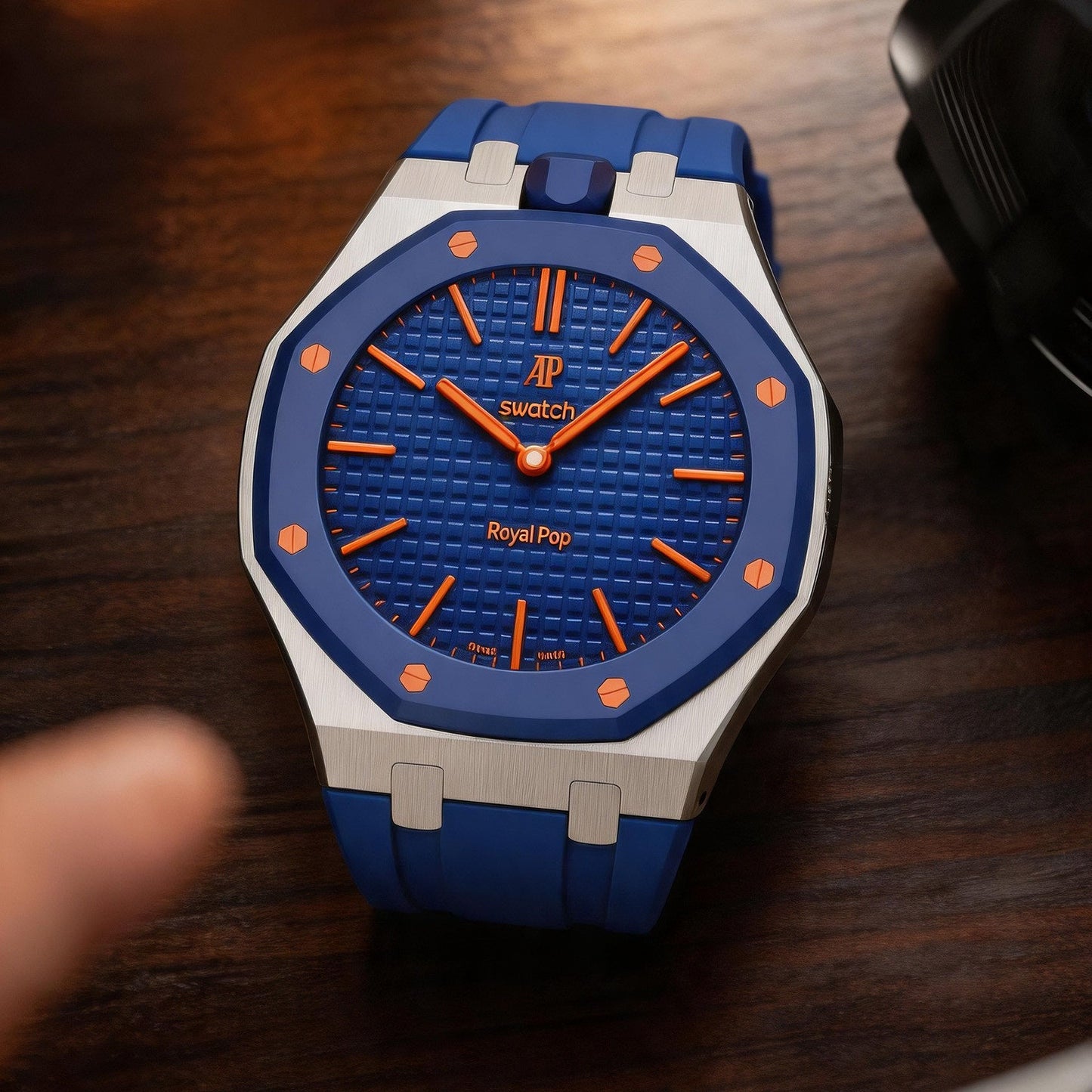 Close-up of the blue and silver Royal Pop watch resting on a wooden surface.