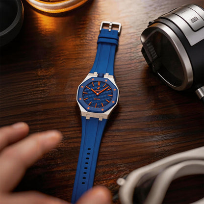Blue and silver Royal Pop watch laid flat on a desk beside a camera and accessories.
